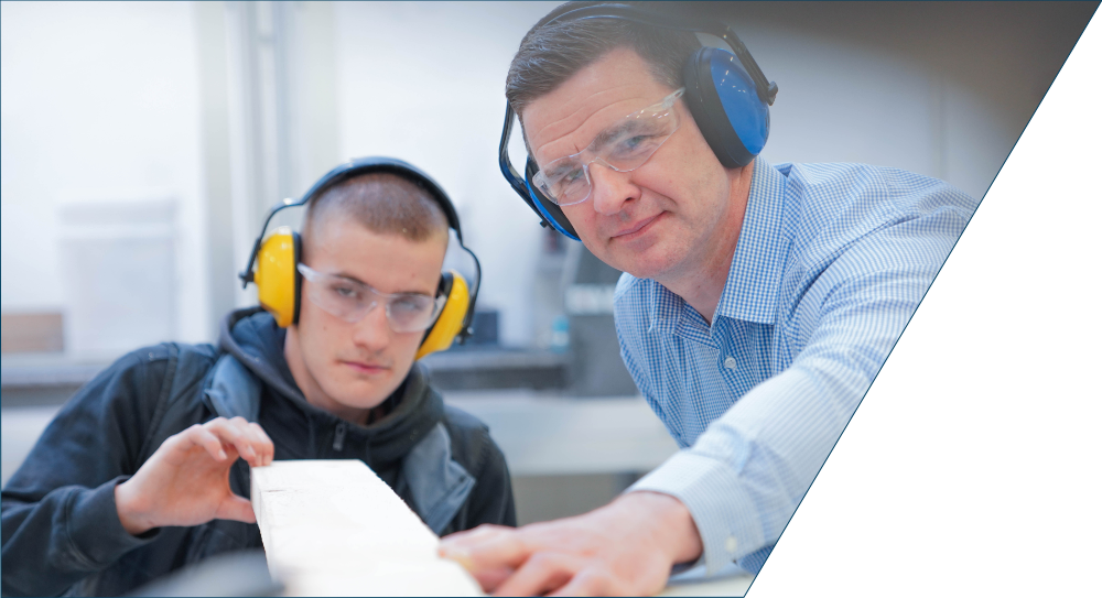 Lecturer and joinery apprentice using machinery.