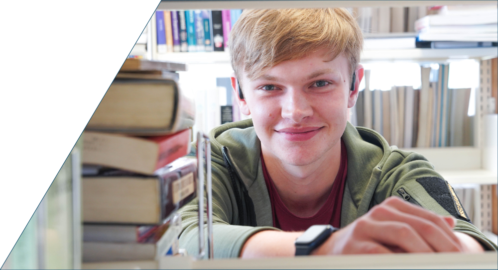 Student looking through a book shelf.